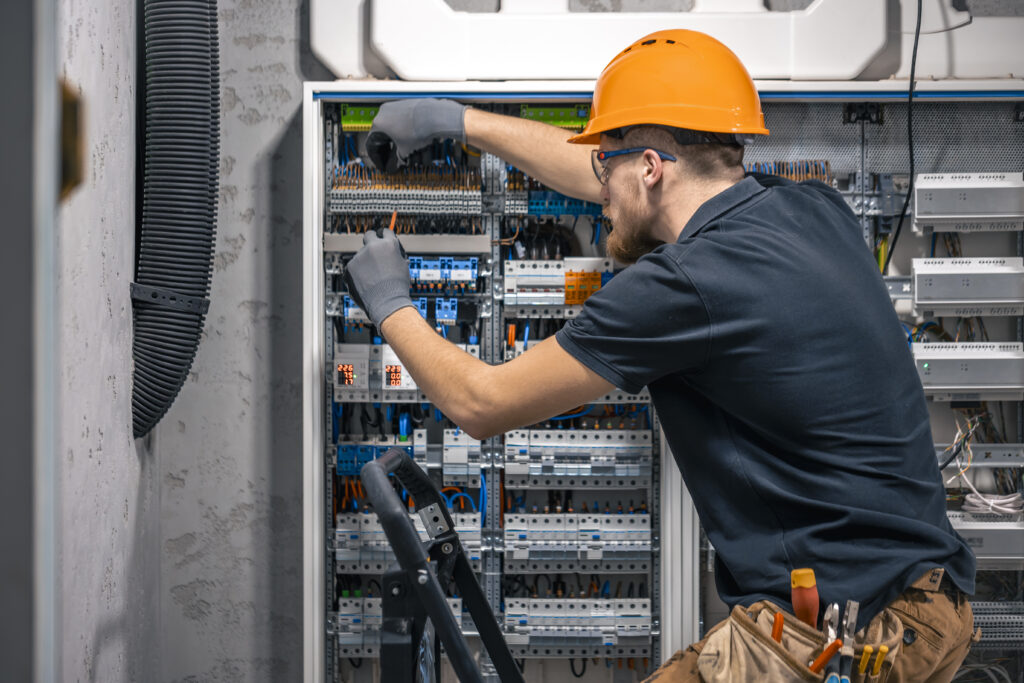male electrician working in a switchboard with fuses.